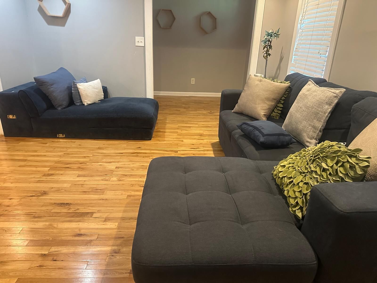 A living room with two dark-colored sofas, a wooden floor, and decorative wall sconces.