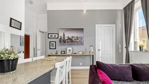 A modern living space with a kitchen area, a dining table, and a sofa with cushions. - Przytulne apartamenty plac Zamkowy (Warsaw)