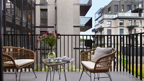 A balcony with wicker chairs, a small table with a vase of flowers, and a view of modern apartment buildings. - Elite Apartments Nadmotławie Prestige (Gdansk)