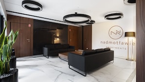 A modern lobby with a black sofa, a coffee table, and a potted plant. - Elite Apartments Nadmotławie Prestige (Gdansk)