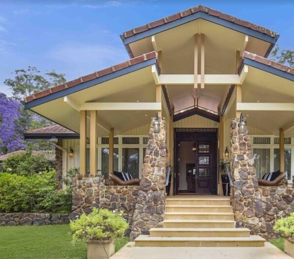 A two-story house with a stone facade, a covered porch, and a front door.