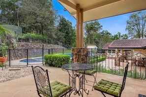 A patio with a stone wall, a round table, and two chairs with green cushions.