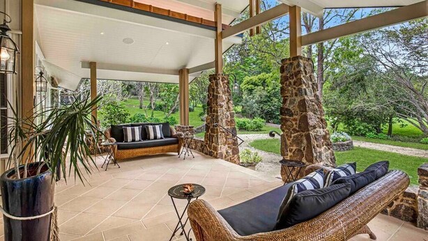 An outdoor patio area with wicker furniture, stone pillars, and a view of the surrounding greenery. - Brookfield Country House, Pool, 7 bedrooms (Upper Brookfield)