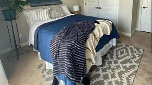 A bedroom with a bed, a decorative wall piece, a white wardrobe, and a patterned rug. - Boutique Style Hotel -Entire Unit (Jeffersonville)