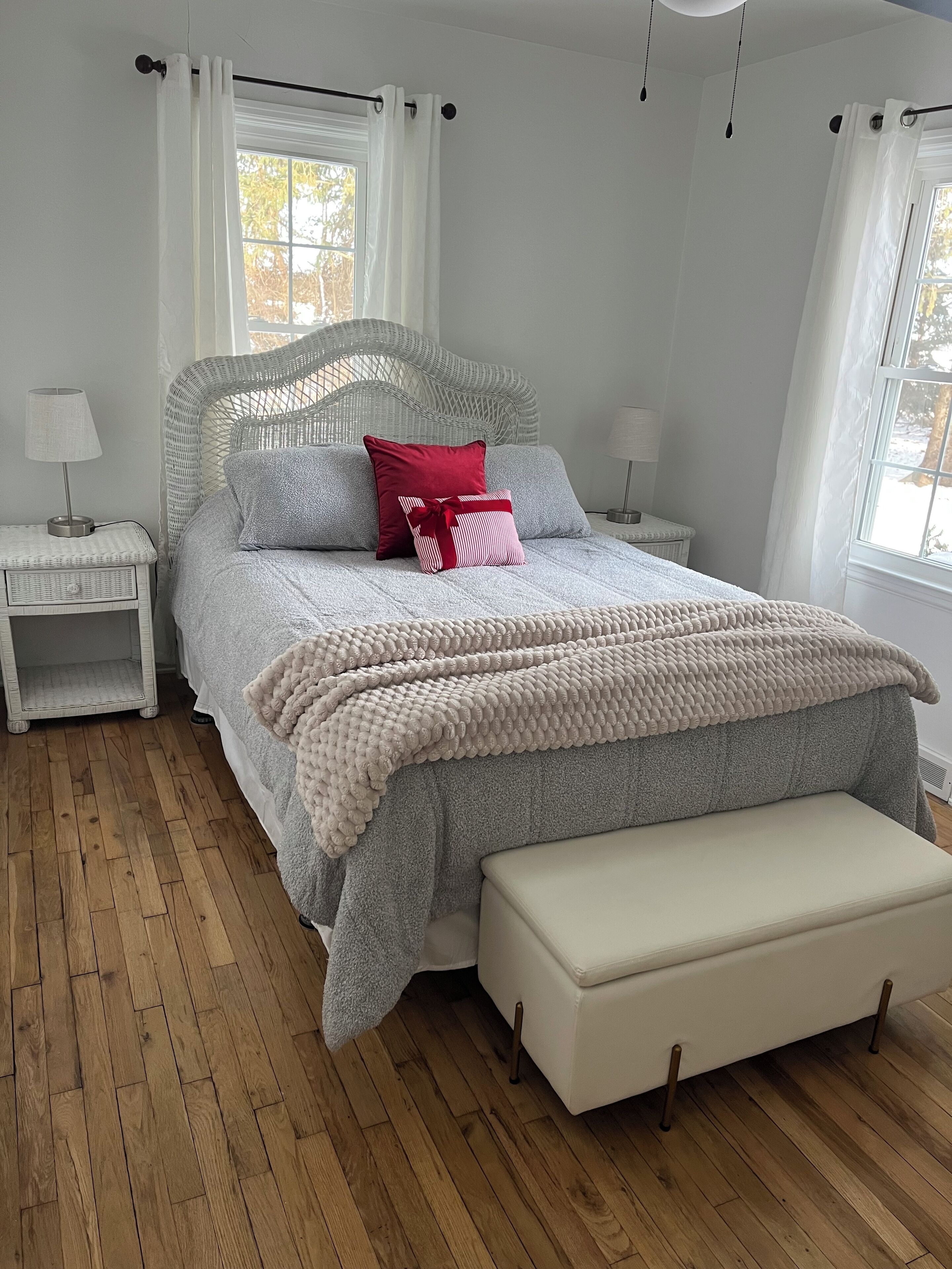 Une chambre à coucher bien aménagée, avec un grand lit, des tables de chevet et un banc.