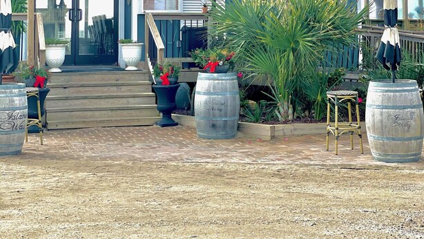 A restaurant with a blue exterior, outdoor seating, and potted plants.