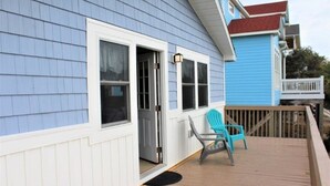A house with a blue exterior, a wooden deck, and a door open to a porch.