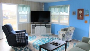 A living room with a television on a stand, a sofa, a chair, and a coffee table.