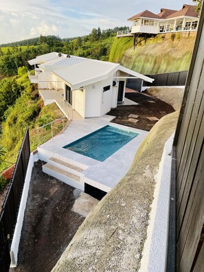 A modern house with a swimming pool, surrounded by lush greenery and hills. - Stunning view with Private Pool (Puna'auia)