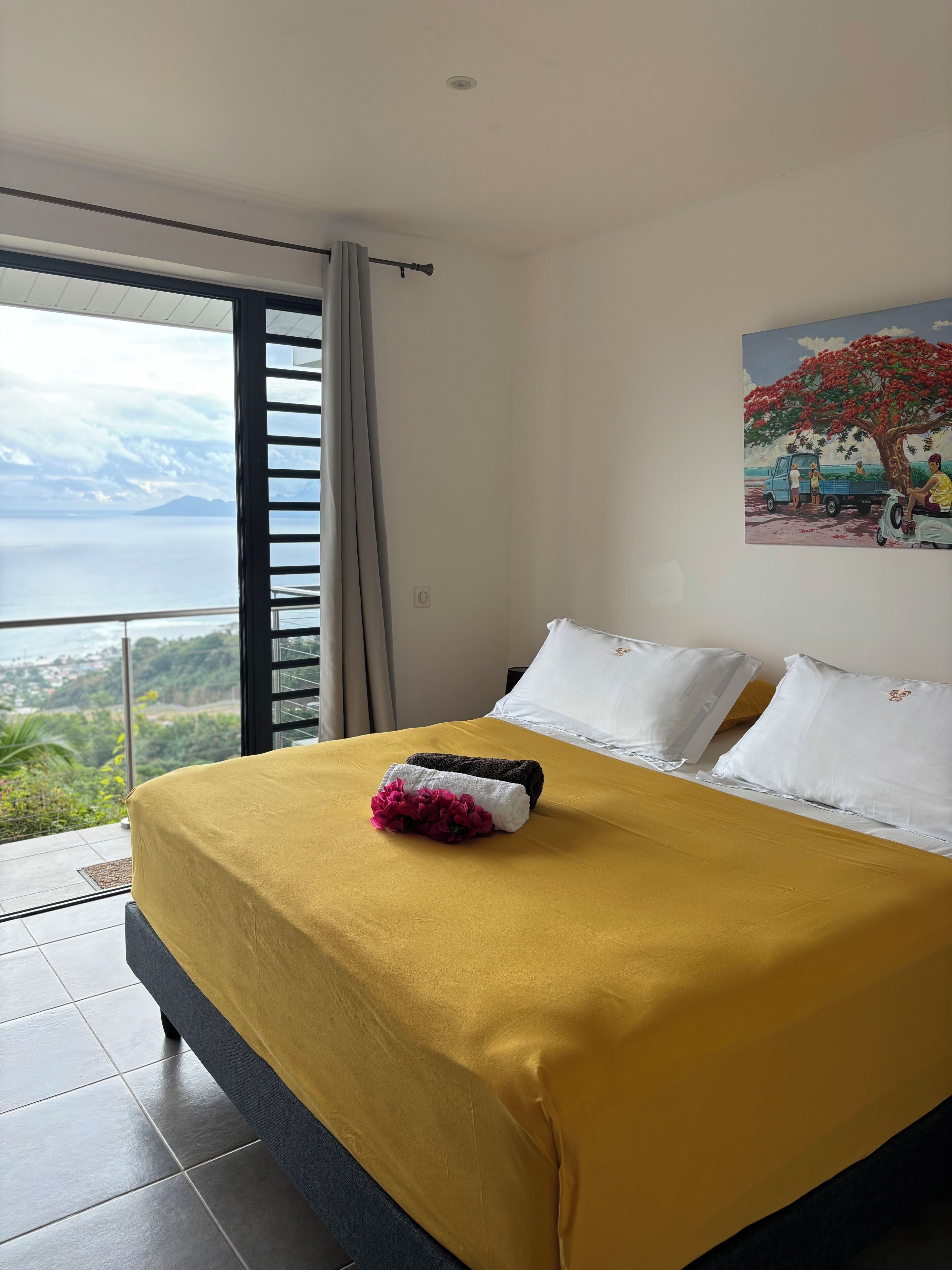 Una camera d'albergo con un letto, un quadro e vista sul mare.