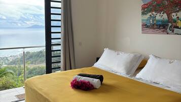 Una camera d'albergo con un letto, un quadro e vista sul mare.