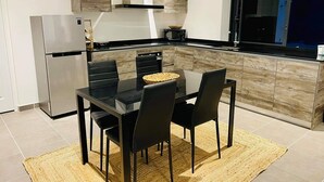 A modern kitchen with a dining table, chairs, and a refrigerator.