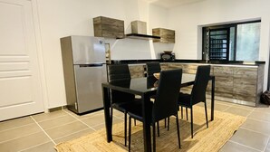A modern kitchen with a dining area, featuring a refrigerator, stove, and a dining table with chairs.