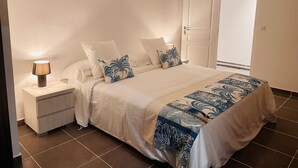 A bedroom with a bed, nightstands, a lamp, and a door.