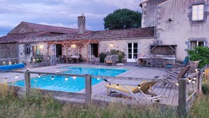A rustic stone building with a wooden deck, a swimming pool, and outdoor seating. - Logis de caractère large reception capacity (Bressuire)