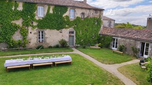 A stone building with ivy-covered walls, a gravel path, and a long table set for dining. - Logis de caractère large reception capacity (Bressuire)
