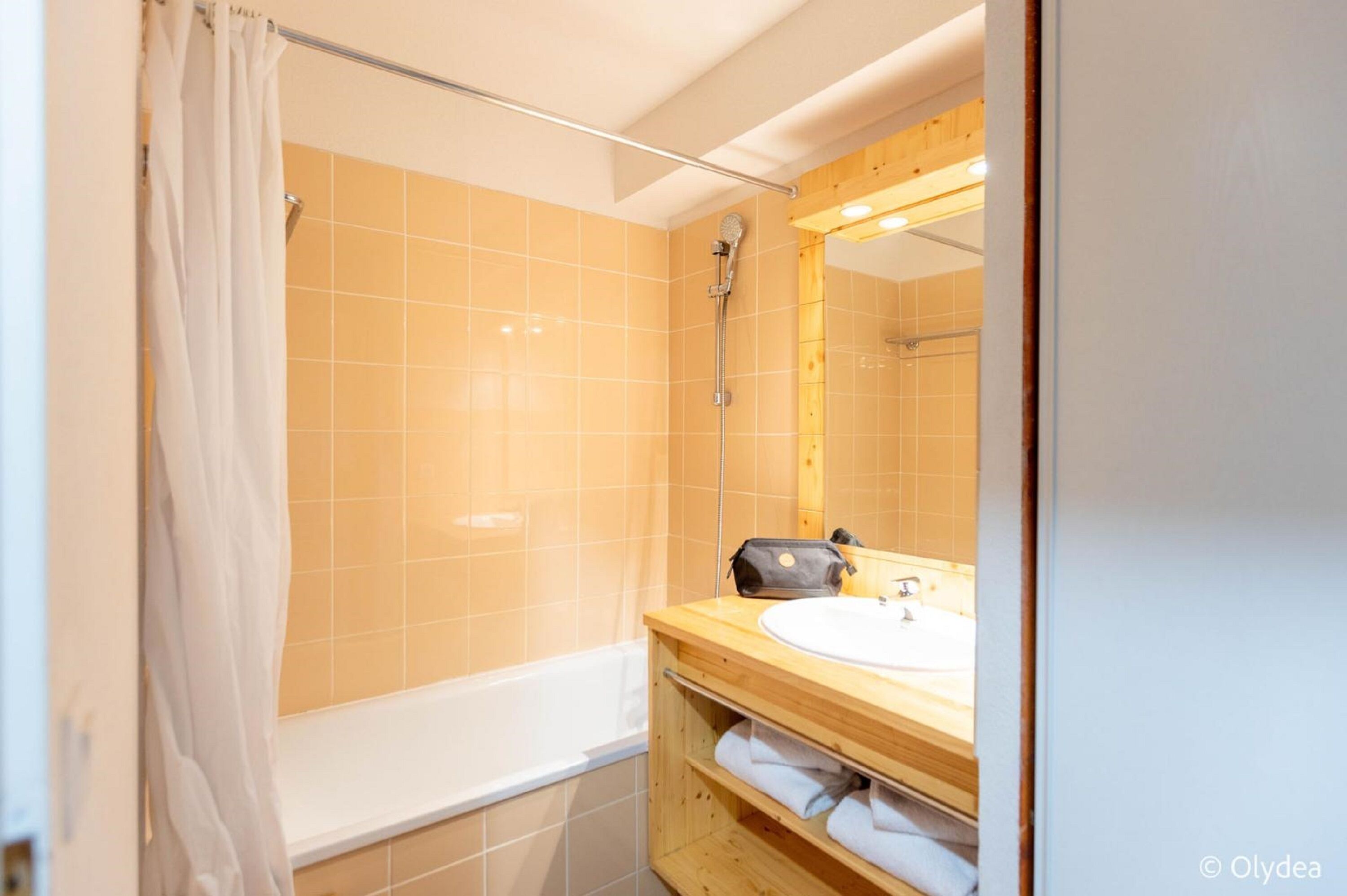 Un baño con bañera, un tocador de madera con lavamanos y una ducha con cortina.