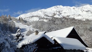 Paisaje nevado de montaña con una cabaña de madera al frente.