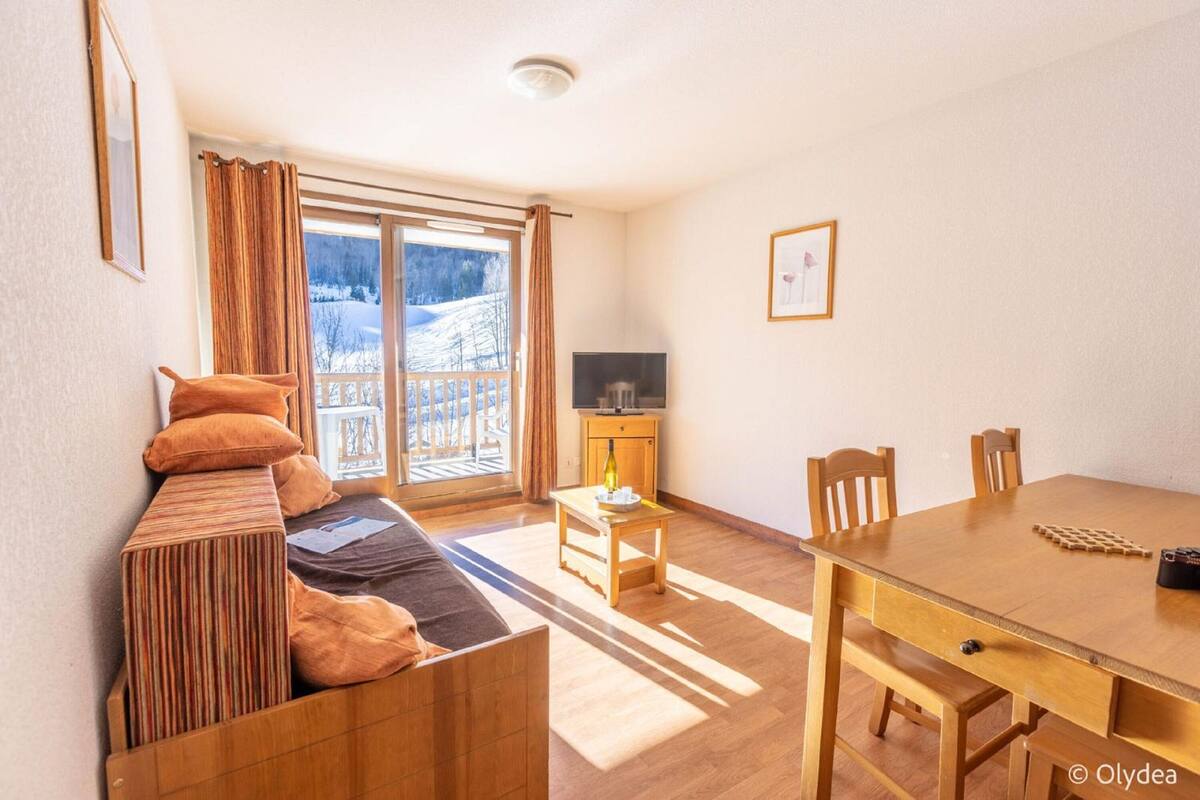 Una habitación acogedora con un sofá, una mesa de comedor de madera y un televisor.