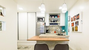 A modern kitchen with a central island, two chairs, and a refrigerator. - Side sea View 3min From the Beach Pj204 (Rio de Janeiro)