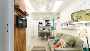 A modern kitchen with a built-in oven and microwave, a dining area with two chairs, and a living room with a sofa and decorative pillows. - Side sea View 3min From the Beach Pj204 (Rio de Janeiro)