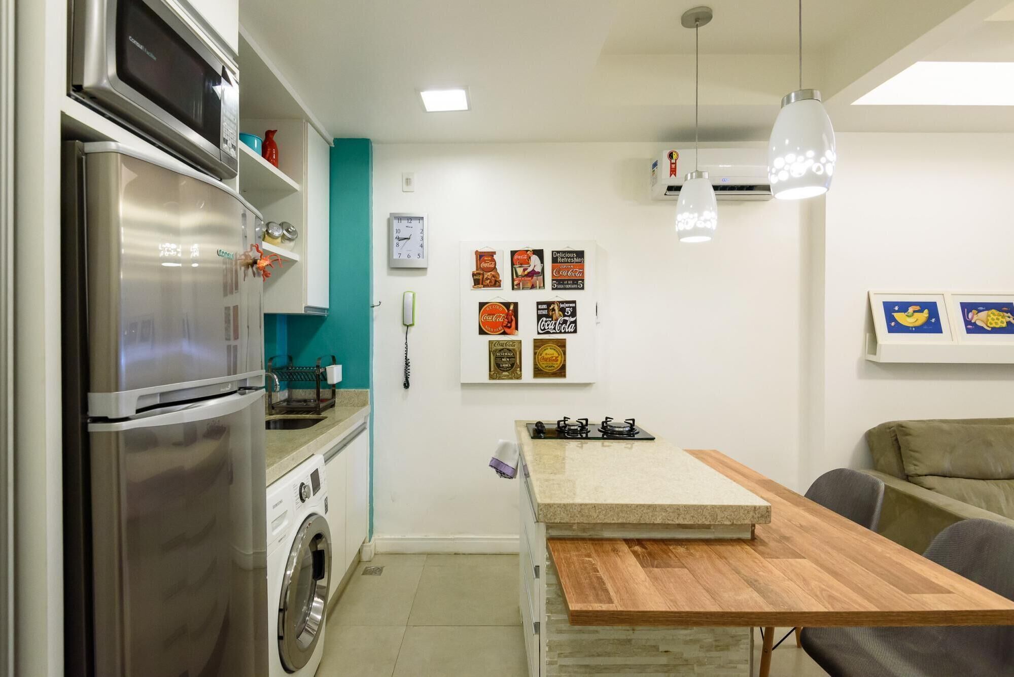 Una cucina compatta con frigorifero in acciaio inox, lavatrice e tavolo da pranzo in legno.