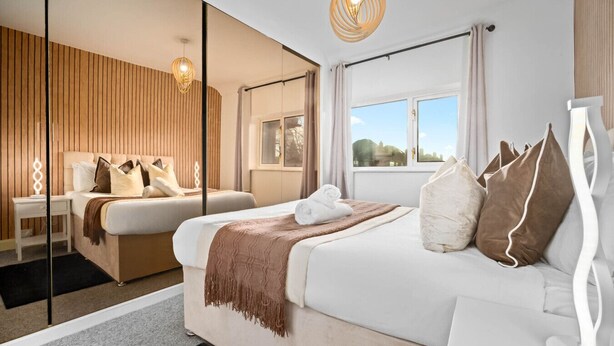 Ett modernt hotellrum med en stor säng, ett sängbord, en spegel och ett fönster med utsikt.