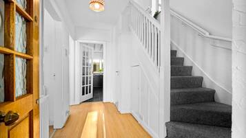 A hallway with a wooden door, a staircase, and a light fixture.