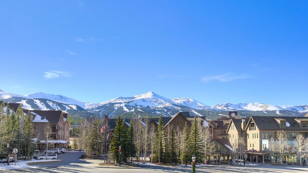 A hotel with a mountain view, a parking lot, and a street with trees. - RATES REDUCED! Dogs Welcome! Stunning Views & Unbeatable Location! MainC (Breckenridge)