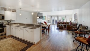 A spacious kitchen with a central island, a dining area with a table and chairs, and a living room with sofas and a coffee table. - RATES REDUCED! Dogs Welcome! Stunning Views & Unbeatable Location! MainC (Breckenridge)