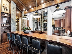 Una cocina moderna con una isla de madera, taburetes de bar e iluminación colgante.