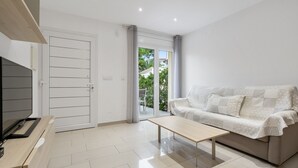 A modern living room with a sofa, a coffee table, a TV, and a sliding glass door leading to a balcony. - La Vida Sin Limites "B" EMP (Empuriabrava)