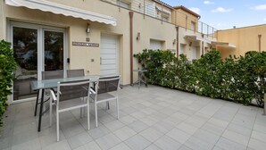 A patio area with a table and chairs, a covered seating area, and a building with a sign reading "ANGELUS SAINTS". - La Vida Sin Limites "B" EMP (Empuriabrava)