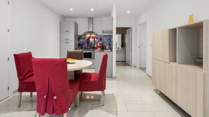 A modern kitchen with white cabinets, a central island, and red chairs. - La Vida Sin Limites "B" EMP (Empuriabrava)