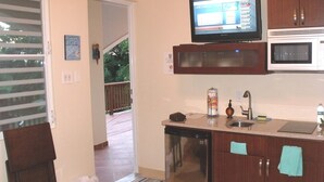 Eine Küche mit Kühlschrank, Mikrowelle und einem Fernseher, der über der Arbeitsfläche angebracht ist.