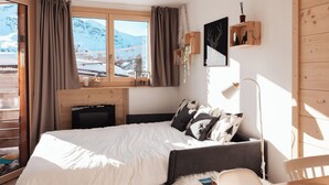 Ein gemütliches Schlafzimmer mit einem Bett, einem Schreibtisch und Blick auf einen verschneiten Berg.