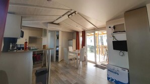 A modern kitchen with a dining area, a large window, and a Philips 2-in-1 TV. - Mobile home 40 m²+veranda in the 3-star vacation park les Dunes de Contis 4 km from the beach (Saint-Julien-en-Born)