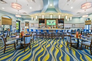 A hotel lobby with a bar area, seating arrangements, and a patterned carpet.