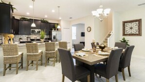 A modern kitchen with dark cabinets, a central island, and pendant lighting. - Beautiful Vacation Home 6BD/6BA with Private Pool CG1524 (Davenport)