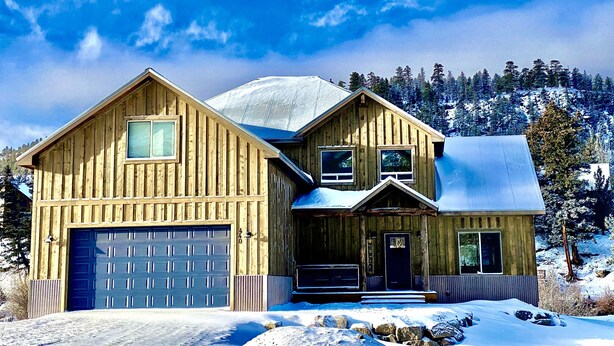 Une cabane en bois avec un garage, un porche et un paysage enneigé.