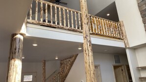 Un intérieur à plusieurs niveaux avec des poutres apparentes, un escalier et un balcon.