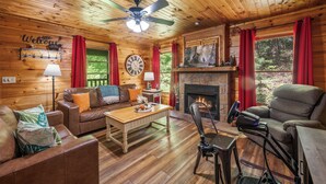 L’intérieur d’un chalet en bois, avec une cheminée, des meubles en cuir, une horloge et une pancarte « Bienvenue ».