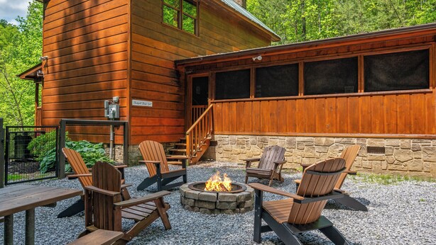 Une cabane en bois avec un mur en pierre, un espace extérieur aménagé pour s’asseoir et un foyer.