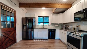 A modern kitchen with white cabinets, stainless steel appliances, and a wooden floor. - Lakefront Cottage Near Crystal Mountain & Rainier (Sumner)