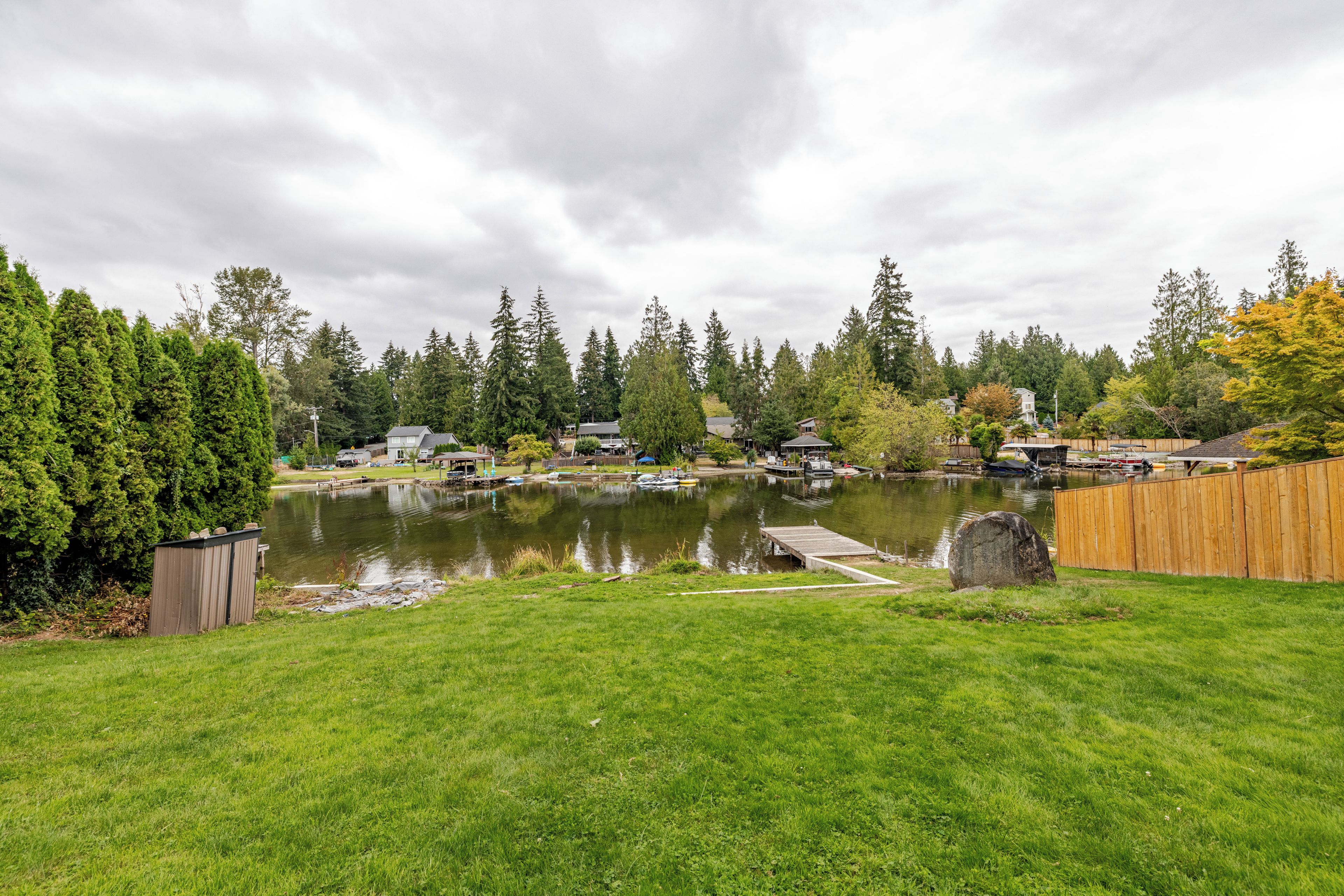 A residential area with a lake, dock, and surrounding greenery.