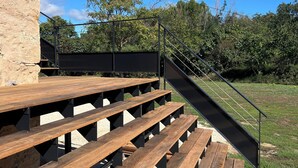 A wooden deck with benches, a staircase, and a metal railing.