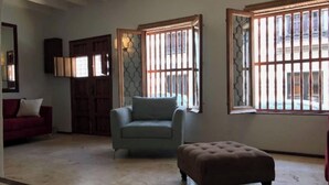 A living room with a sofa, armchair, ottoman, and a large window with bars. - Luxury House in Old San Juan (San Juan)