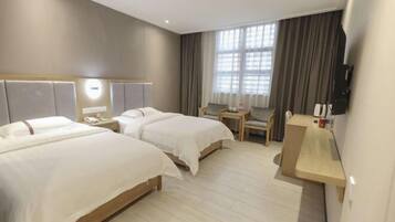 Une chambre d’hôtel avec deux lits, un bureau, une chaise, une télévision et une fenêtre avec des rideaux.