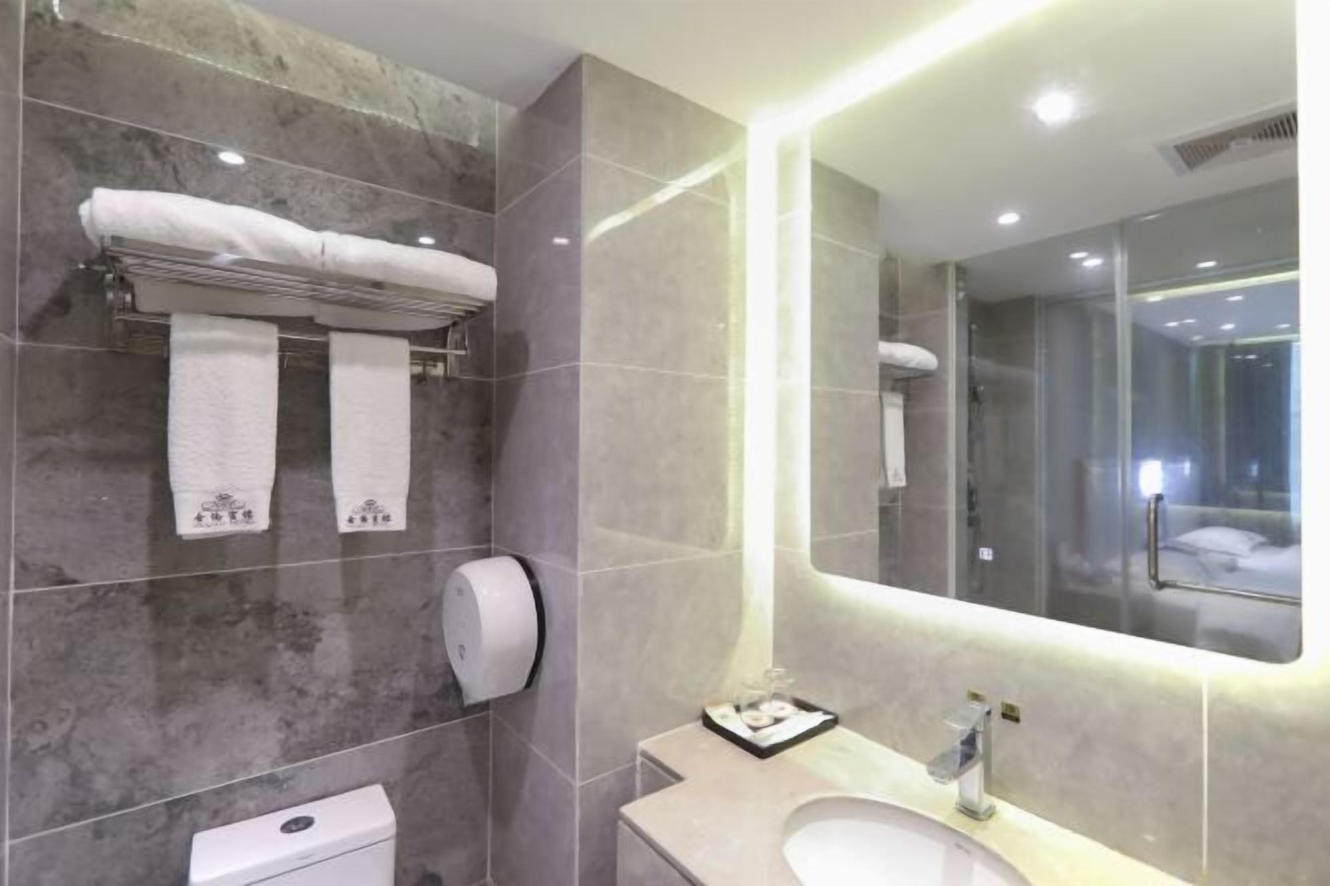 Une salle de bain moderne avec un mur en marbre, des toilettes, un lavabo et un grand miroir.