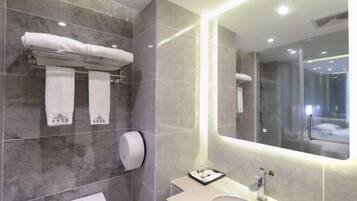 Une salle de bain moderne avec un mur en marbre, des toilettes, un lavabo et un grand miroir.